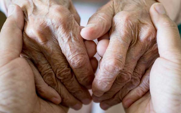 A caregiver holding hands with an elderly patient