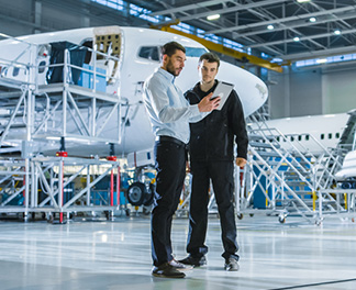 Two men in an air hanger looking at a tablet computer