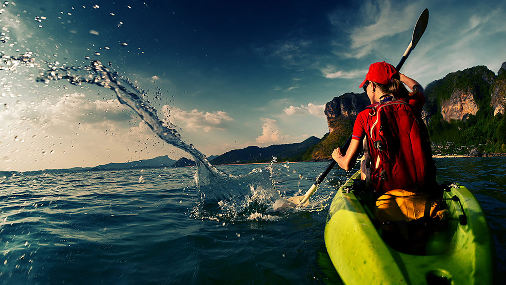 Woman in a kayak with a paddle making a splash