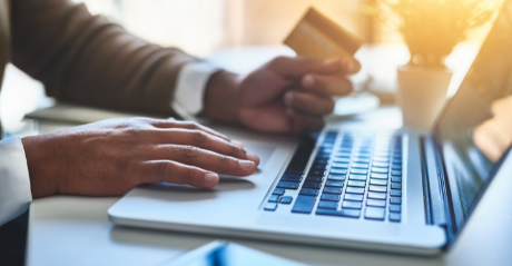 Person holding a credit card while working on a laptop