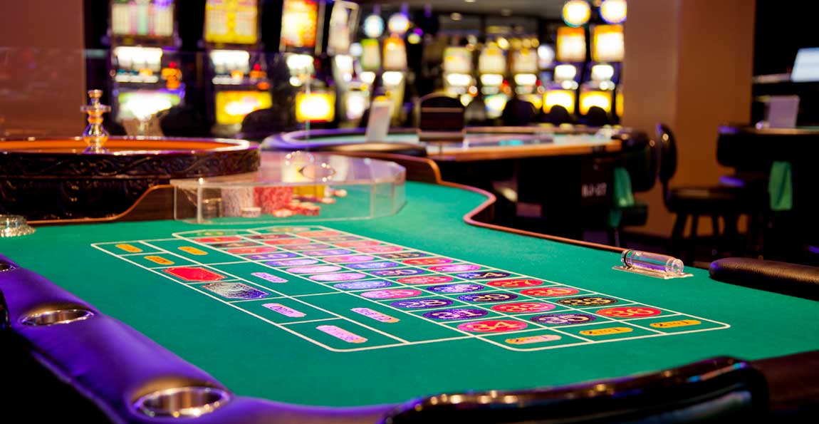 A roulette table and slot machines on a casino floor