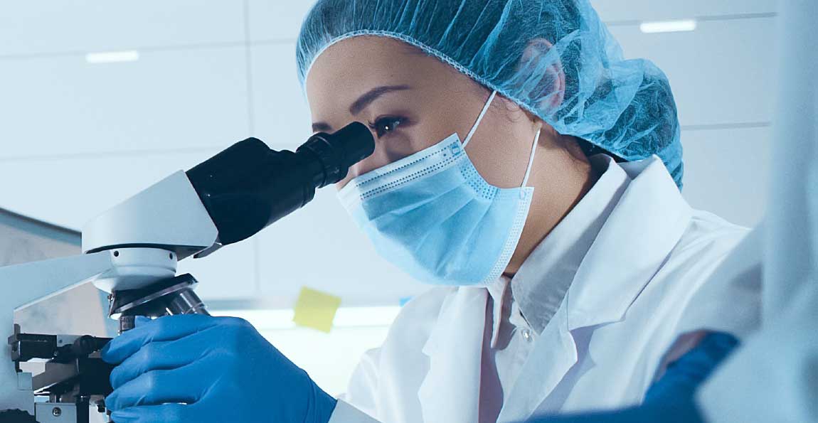 A laboratory technician looking into a microscope
