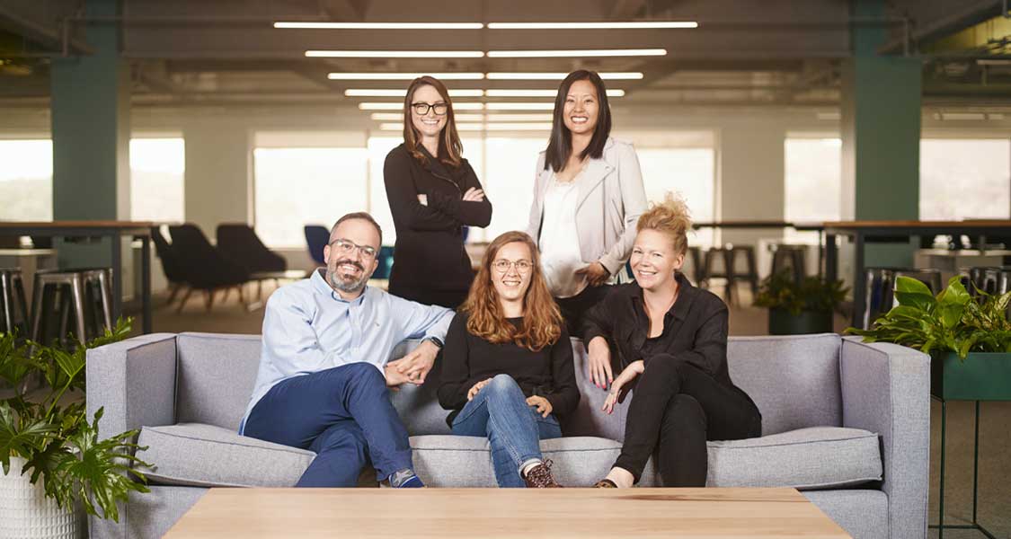Five professional men and women smiling for a team photo