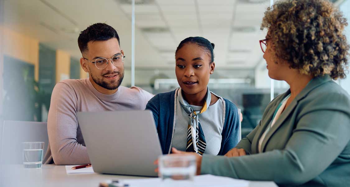 Three small business owners looking at small business banking information on a laptop