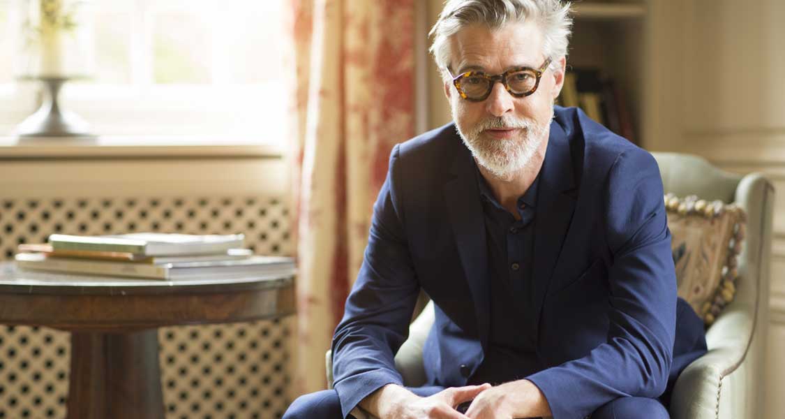 A white-haired man sitting in a well-lit room. 