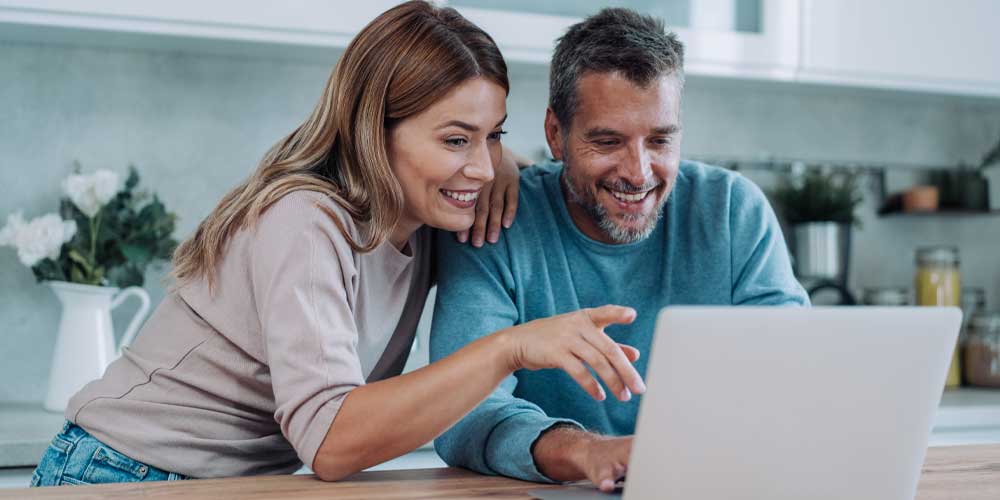 A man and woman looking at their bank account on a laptop