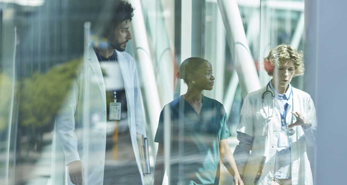Image of three healthcare professionals walking and talking