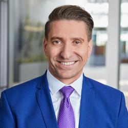 A man in a blue suit smiling for a photo