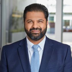 A man in a dark suit smiling for a photo