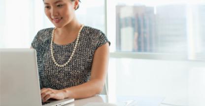 Business woman smiling while typing on her laptop