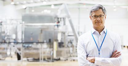 Businessman smiling at camera inside large warehouse facility