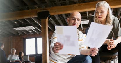 Two people looking at a shared piece of paper.