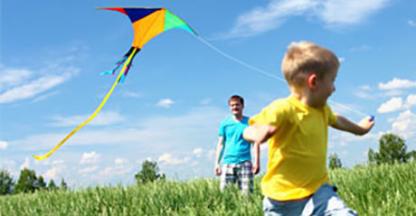young boy running in a field with a kite