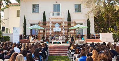 People sitting on a lawn watching a speaker present