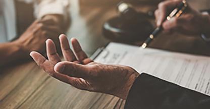 Closeup view of two people's hands while they are working at a shared desk.