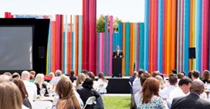 Man presenting at a podium outside