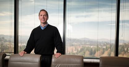 Charles Allen standing in a conference room and smiling at the camera