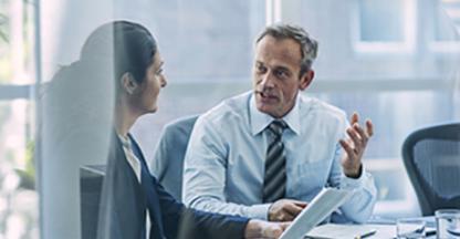 Two businesspeople talking while seated at a conference room table