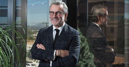 CEO with arms crossed standing in front of glass office