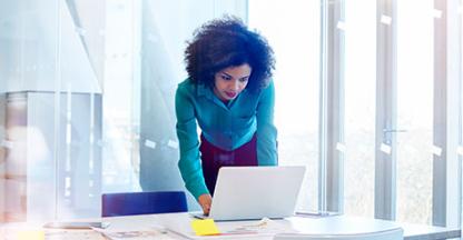 Woman standing up looking down at a computer