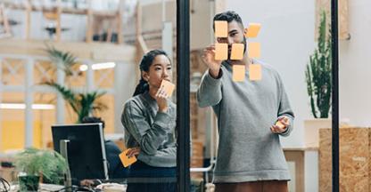 Two people working in a conference room planning using post-it notes