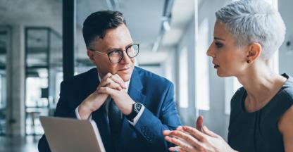 Business man and woman leaning on table smiling and talking