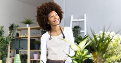 Black woman florist looking at a piece of paper in her shop. 