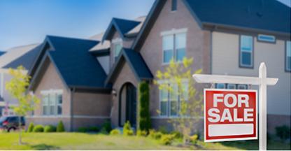 Close up photo of a suburban house with a for sale sign in the yard.