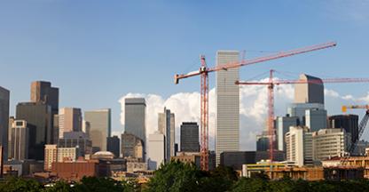 Photo of the Denver skyline with cranes in the foreground. 