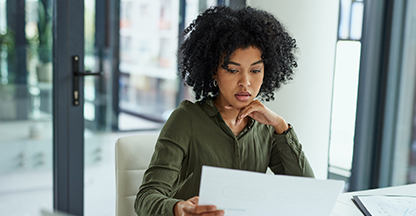 Black woman sitting at a desk looking at a report.