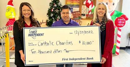 Three representatives from Catholic Charities holding a donation check from First Independent Bank