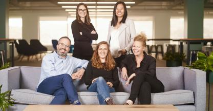 Five professional men and women smiling for a team photo