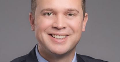 A man in a suit smiling for a photo