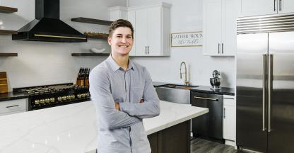 A young man standing in a modern, recently-renovated kitchen