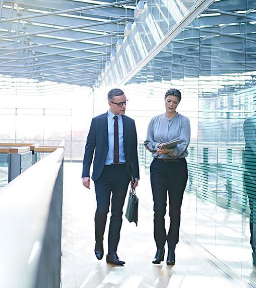 Two business people walking and looking at a shared document