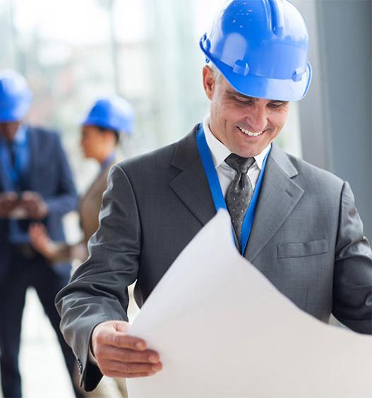 Businessman in a suit and hardhat looking at construction plans