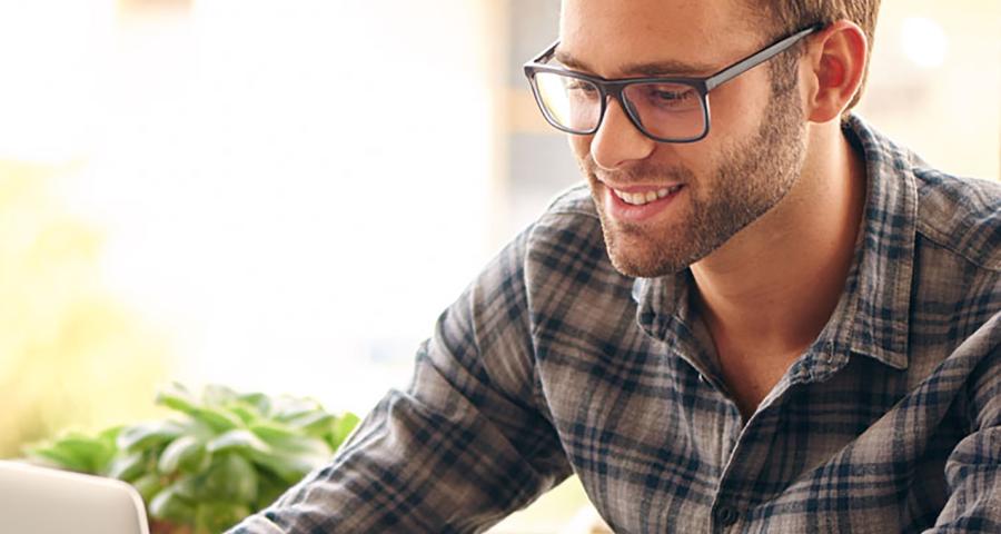 Man smiling while look at and working on a laptop computer