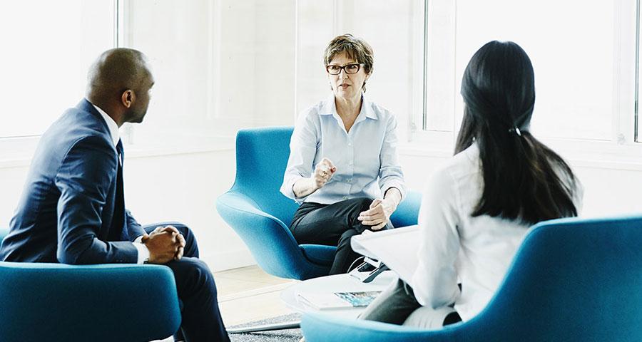 Three business people speaking in a shared workspace