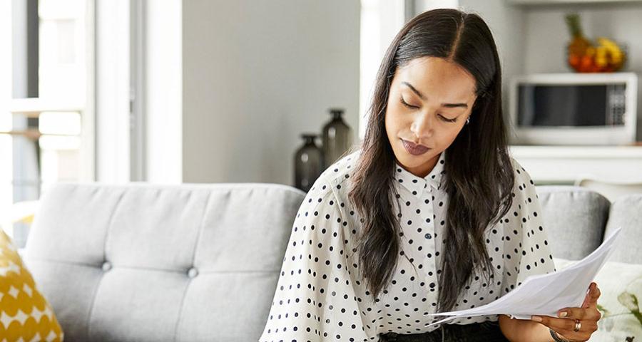 Young woman working on paperwork while sitting on a couch
