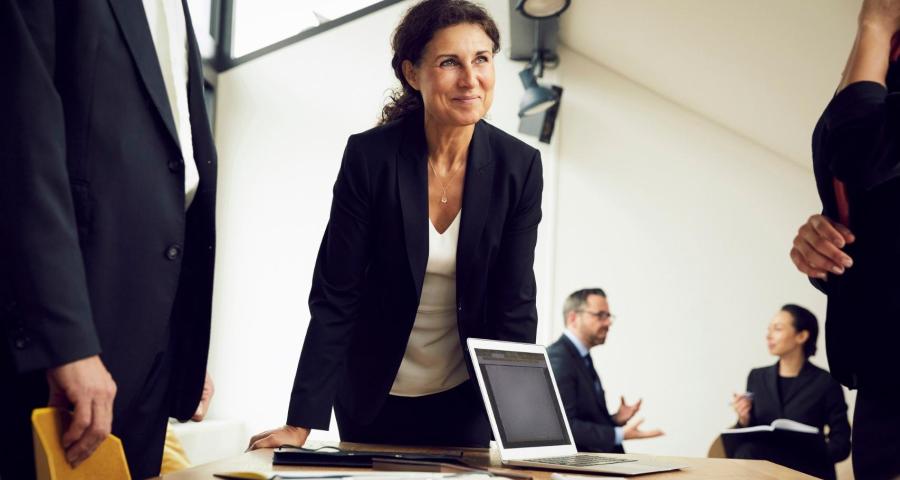 Business woman smiling and leaning against a table