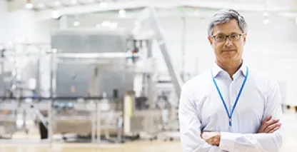 Businessman smiling at camera inside large warehouse facility