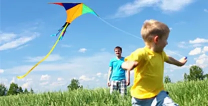 young boy running in a field with a kite