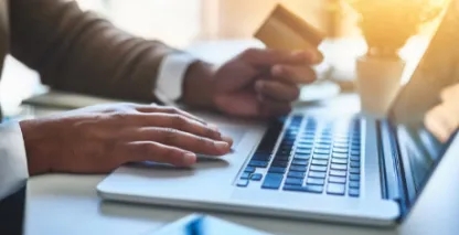 Person holding a credit card while working on a laptop