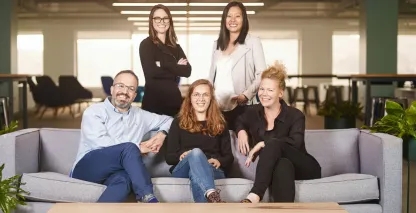 Five professional men and women smiling for a team photo