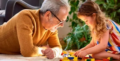 A grandfather playing on the floor with his grandchild
