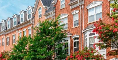 A row of red brick homes on a sunny residential street.