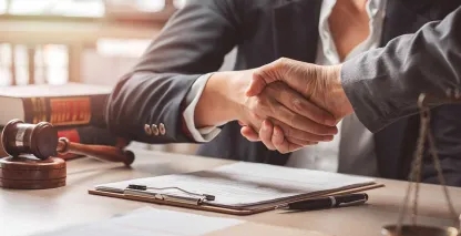Two business men shaking hands over a document