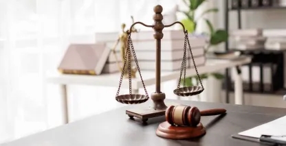 A judge's gavel and the scales of justice atop a shiny desk. 
