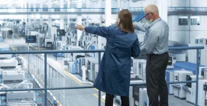 Two manufacturing executives looking out over a vast manufacturing plant
