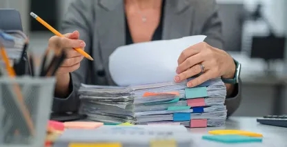 Woman sitting at a desk with a pile of files